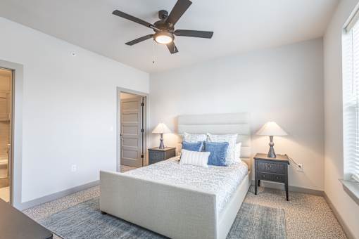 A bedroom with a bed, two lamps, and a ceiling fan.