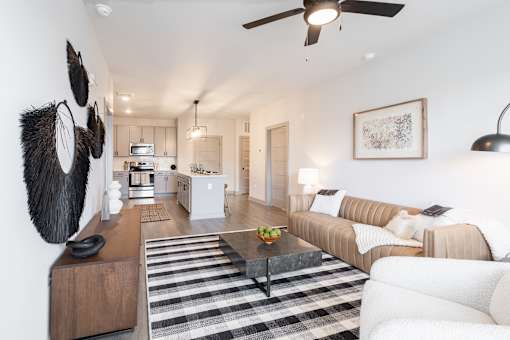 A modern living room with a striped rug and a ceiling fan.