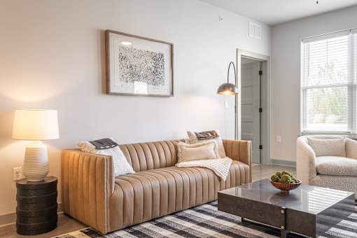 A living room with a brown couch, a coffee table, and a lamp.
