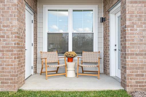 Two chairs and a planter sit on a porch.