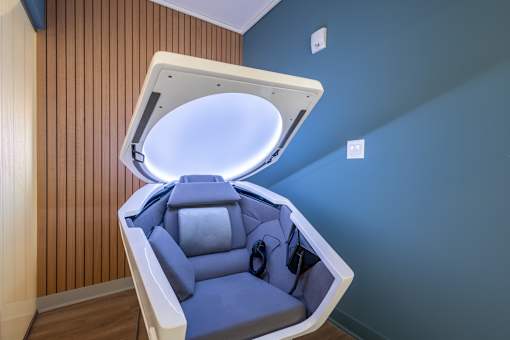 A modern, blue-toned room with a SomaDome meditation pod.