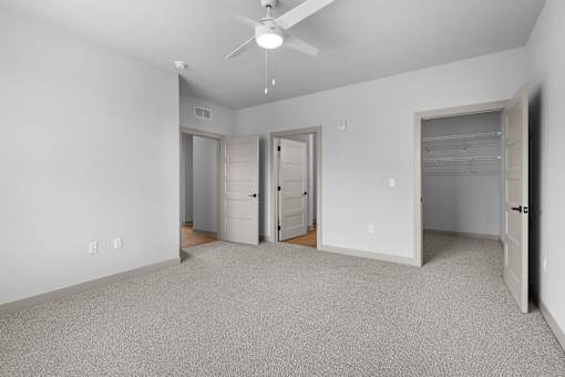 A spacious room with a ceiling fan and carpeted floor.