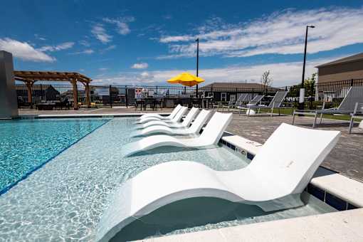 Pool area with white lounge chairs in water at Allure Apartments, Whiteland, 46184