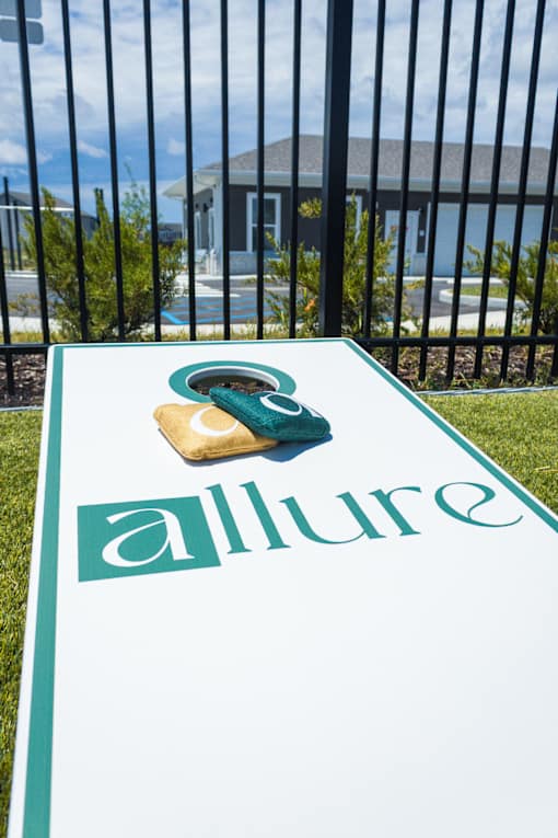 Cornhole board on lawn near pool and clubhouse at Allure Apartments, Whiteland, 46184