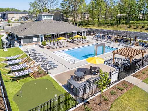 A large outdoor pool area with a small putting green and a clubhouse.