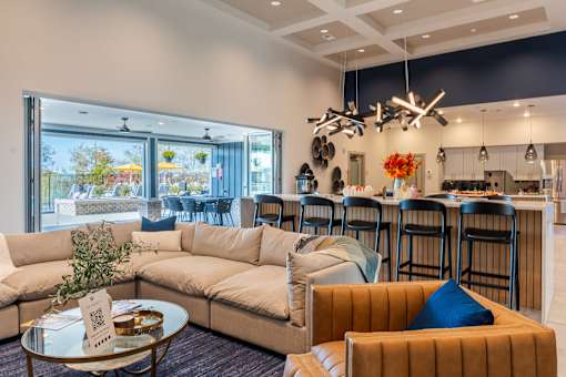 A modern living room with a large window overlooking a patio at The Warren Apartments, Jeffersonville, IN