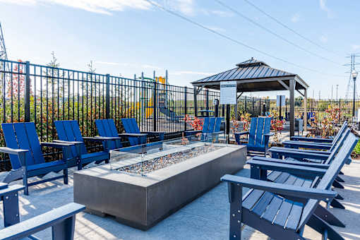 A gazebo is surrounded by blue chairs and a fire pit at The Warren Apartments, Jeffersonville, IN