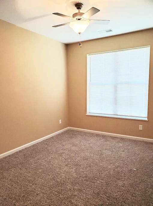 A room with a ceiling fan and a window with blinds.
