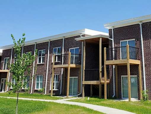A row of red brick apartment buildings with balconies.