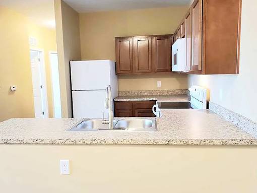 A kitchen with a white refrigerator and brown cabinets.