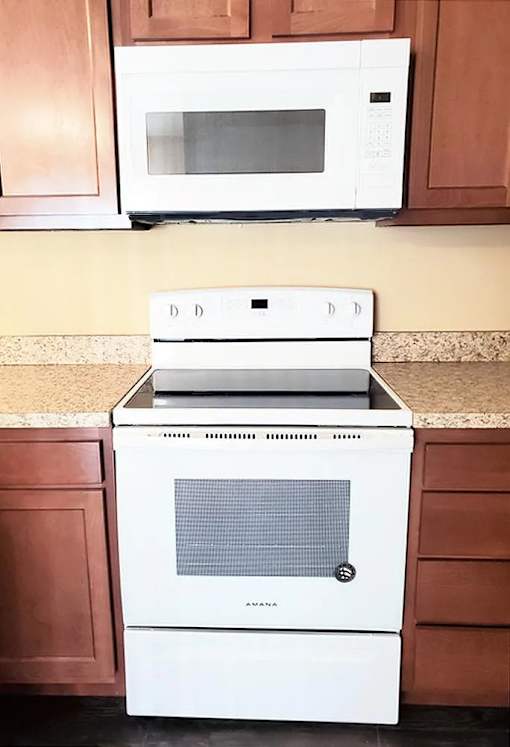 A white microwave oven is on top of a white oven.