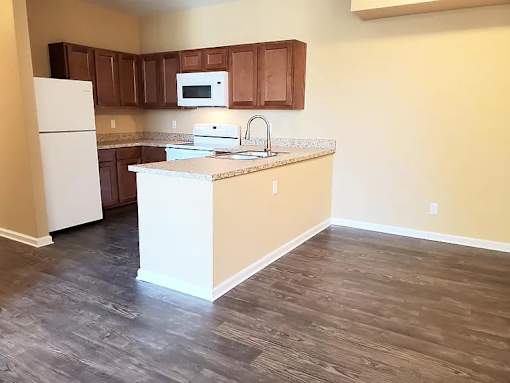 A kitchen with a white refrigerator and brown cabinets.