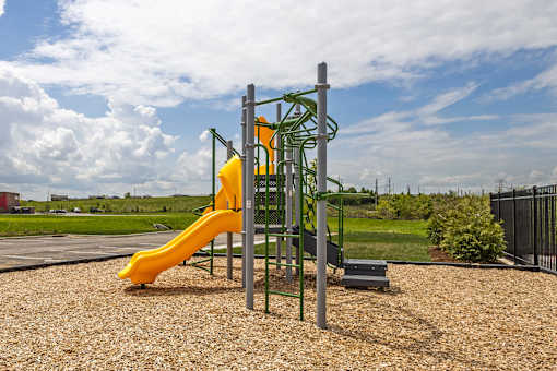 A playground with a yellow slide and a green climbing structure.