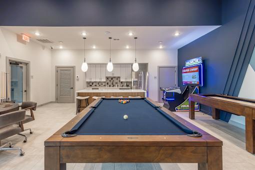 A pool table is in the middle of a room with a TV on the wall.