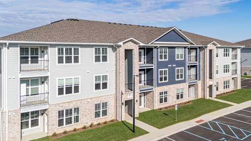 Apartment complex with a parking lot in front.