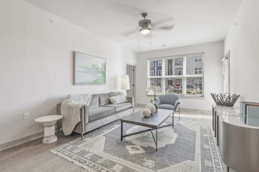 A living room with a grey couch, a coffee table, and a ceiling fan at The Warren Apartments, Jeffersonville, IN