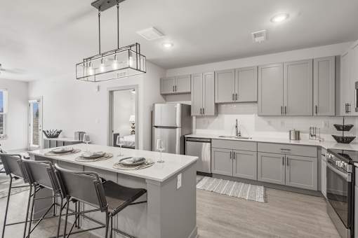 A modern kitchen with a dining table set for four at The Warren Apartments, Jeffersonville, IN