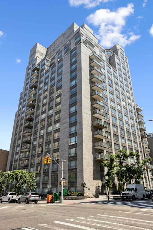 A tall building with many windows is located on a street corner.