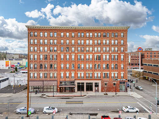A large red brick building with many windows is in the city street. at 206 Flats Apartments, Washington, 99201
