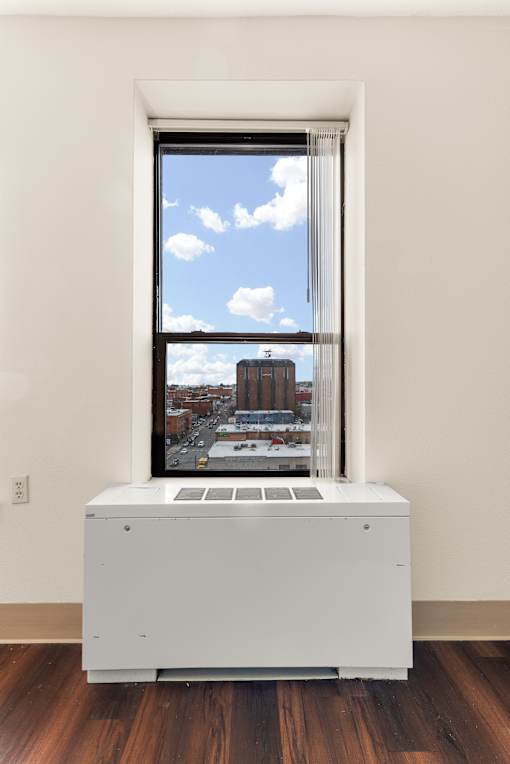 A window with a view of a cityscape and a white air conditioning unit in front of it at 206 Flats Apartments, Spokane, Washington