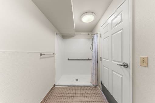 A white bathroom with a tiled floor and a shower at 206 Flats Apartments, Spokane 99201