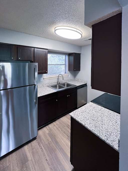 an empty kitchen with granite counter tops and stainless steel refrigerator