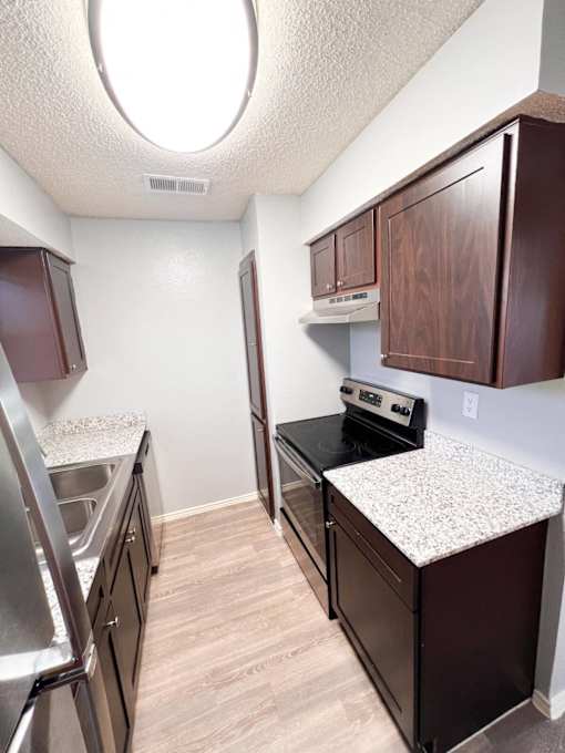 a kitchen with granite countertops and stainless steel appliances and wooden cabinets