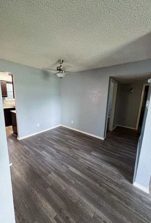 an empty living room with wood floors and a ceiling fan