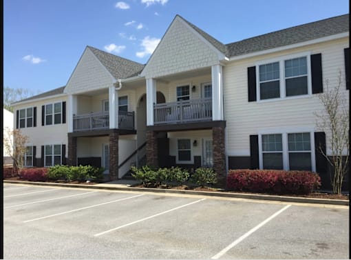 A white building with a parking lot in front.