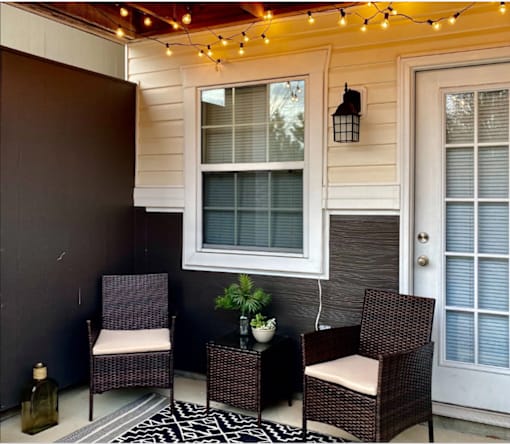 A patio with a chair, table, and a plant.
