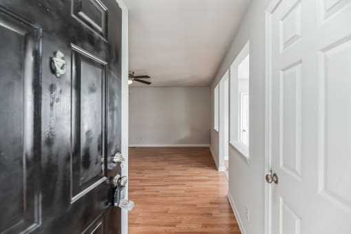the hallway of a home with a black door and wood floors