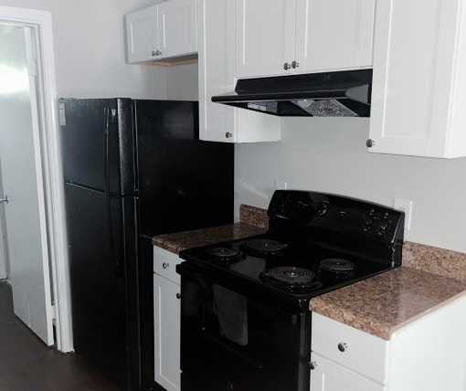 a kitchen with white cabinets and black appliances