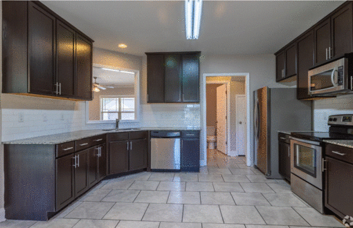 a kitchen with dark cabinets and a tile floor