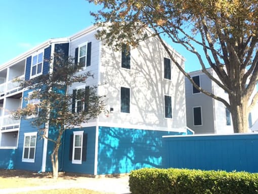 a white and blue apartment building with trees in front of it