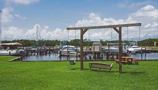 a park with a bench and swing next to a marina