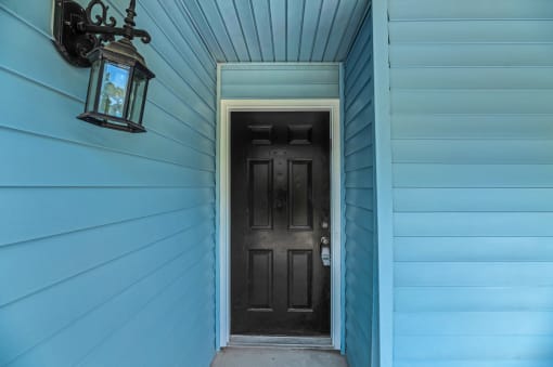 the front door of a blue house with a black door
