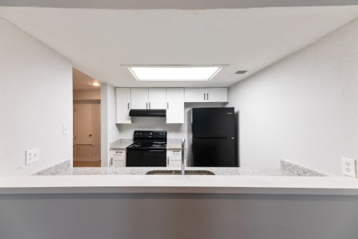 an empty kitchen with a counter top and a black refrigerator