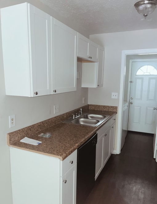 a kitchen with white cabinets and a black dishwasher