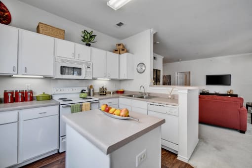 a kitchen with white cabinets and appliances and a bowl of fruit