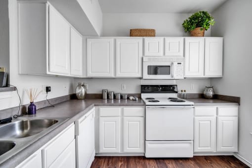 a kitchen with white cabinets and appliances and a sink