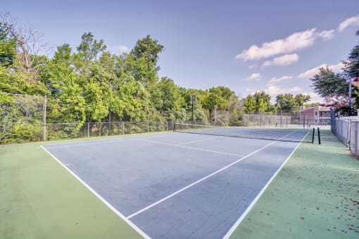 a tennis court with a fenced in area and trees