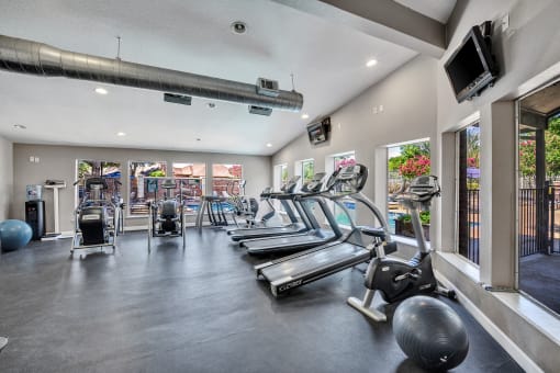 the gym has cardio equipment and glass windows