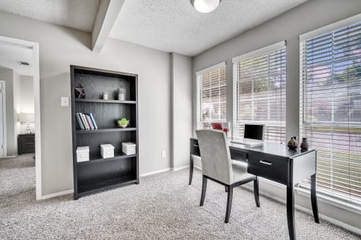 an office with large windows and a desk with a chair