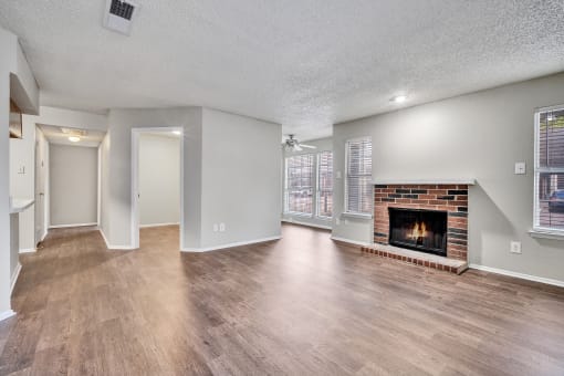 an empty living room with a fireplace and hardwood floors