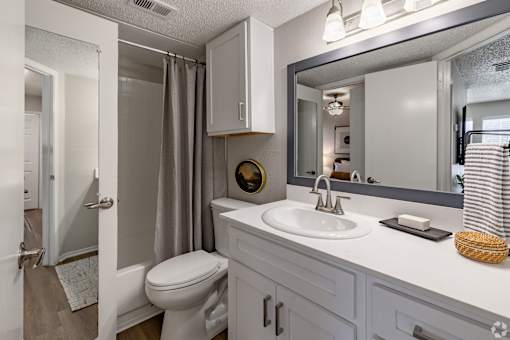 Bathroom with white vanity and framed mirror at Highland Park Apartments, Texas