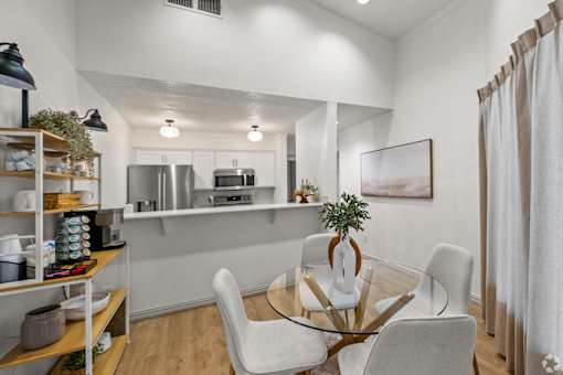 A modern kitchen with a glass table and white chairs.