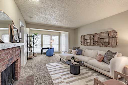 Living room with brick fireplace and woven wall art at Highland Park Apartments, Fort Worth, Texas