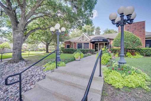 the front of a house with stairs and a sidewalk and lamp posts