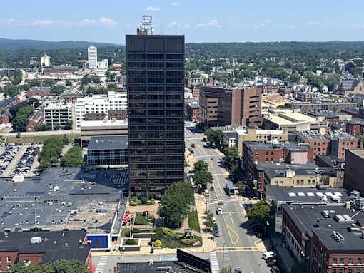 A tall building stands in the middle of a city intersection.