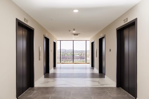 a long corridor with black doors and a view of the mountains